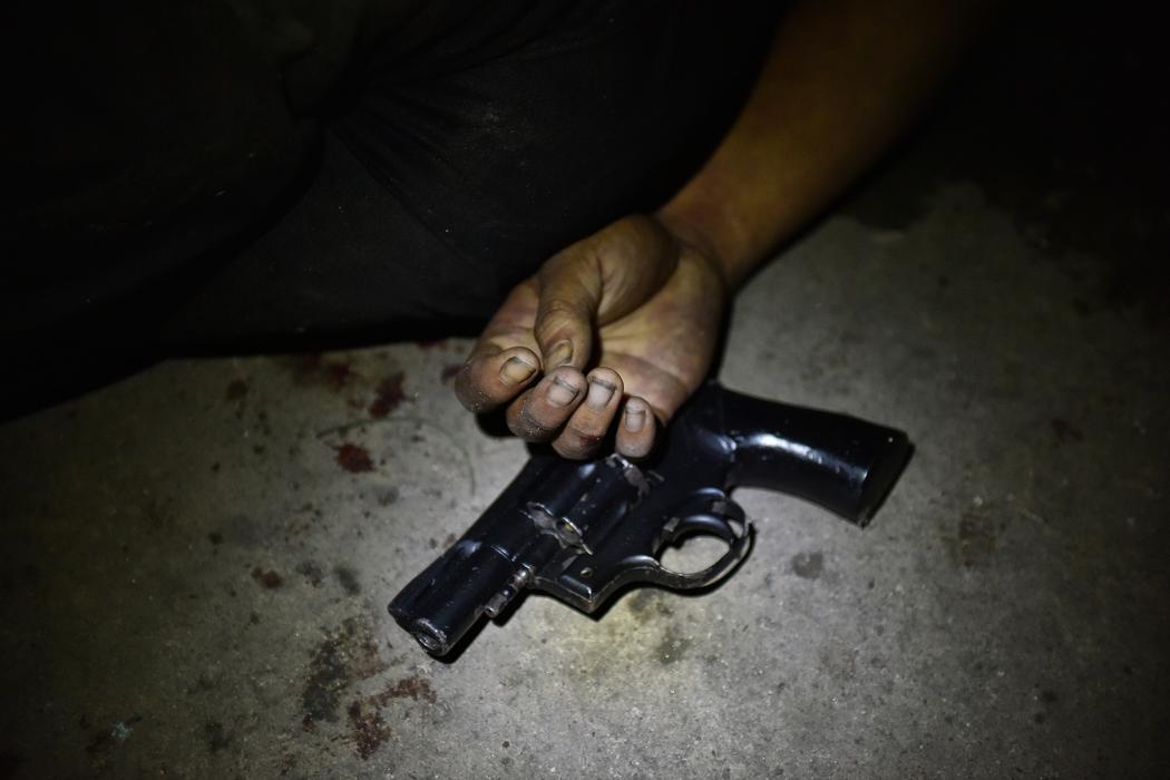 Un revolver de calibre 38 se trouve près de la main d'un suspect sans vie, lié à la drogue, après une fusillade avec la police à Manille, le 17 août 2016. Photo de Jes Aznar.