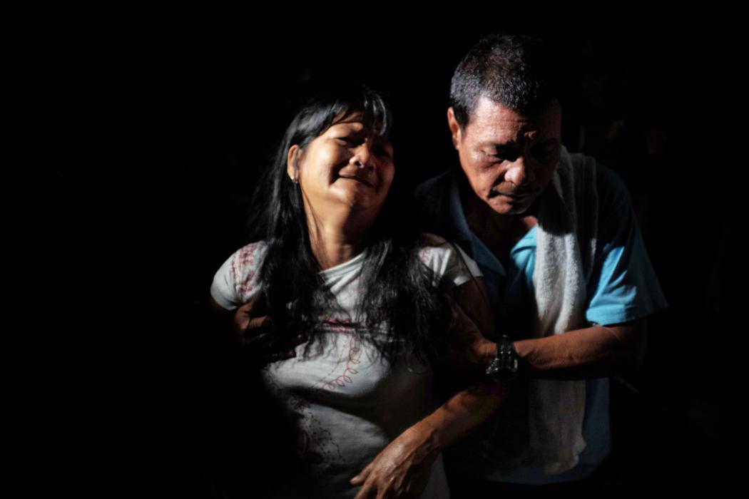 Nestor Hilbano réconforte sa femme, Alma, après avoir vu son fils à l'intérieur d'un sac de corps dans une allée sombre à Tatalon. Ils sont les parents de Richard Hilbano, 32 ans, qui a été abattu par la police dans une opération contre les trafiques de drogues illégaux. La police sur les lieux a rapporté que Richard était en plein deal avec trois autres personnes quand ils ont tous été abattus et tués. Photo de Jes Aznar.