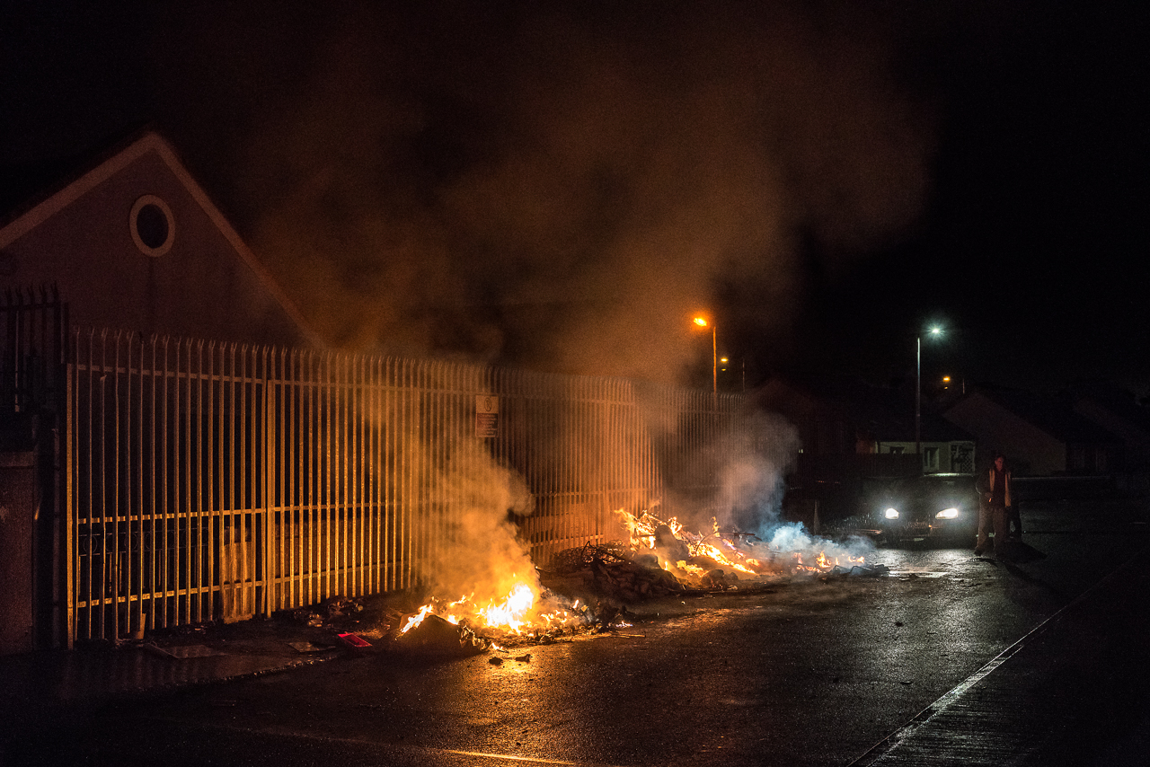 Vor einem Zaun brennen Feuer