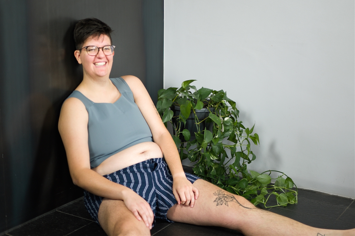 Tilke Wouters sitting on the floor wearing boxers and a mid-length grey binder.