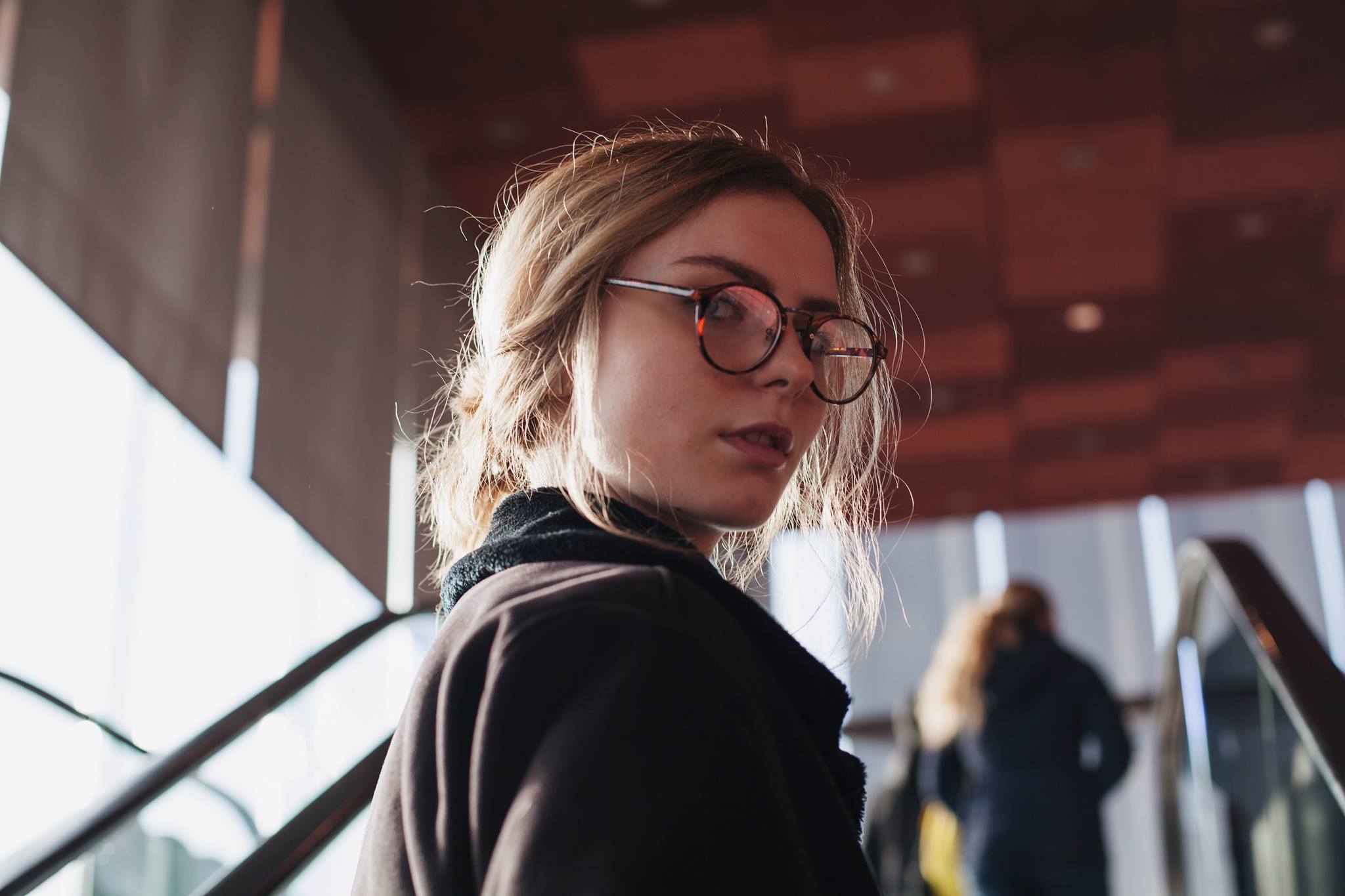 Julia, long hair in an updo, wearing glasses and looking over her shoulder.