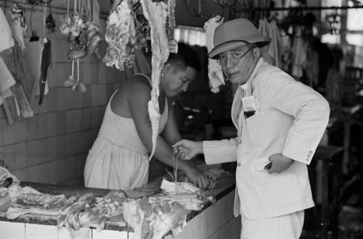man in western suit in butcher shop in 1940s singapore