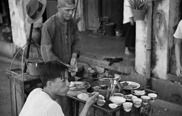 man eats from street hawker in 1940s singapore