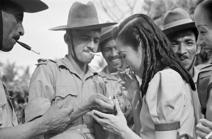 man from indian hospital corps lights woman's cigarette in 1940s singapore