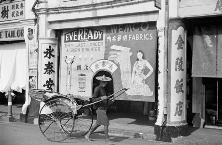 rickshaw puller working in front of chinese shops in 1940s singapore