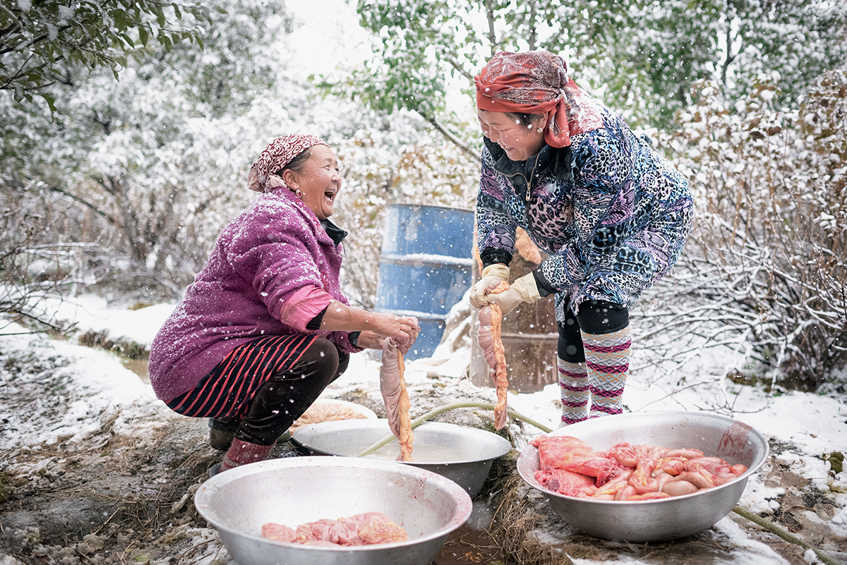 Due donne ridono mentre lavorano alcuni intestini di cavallo, in Kirghizistan, nel 2016.