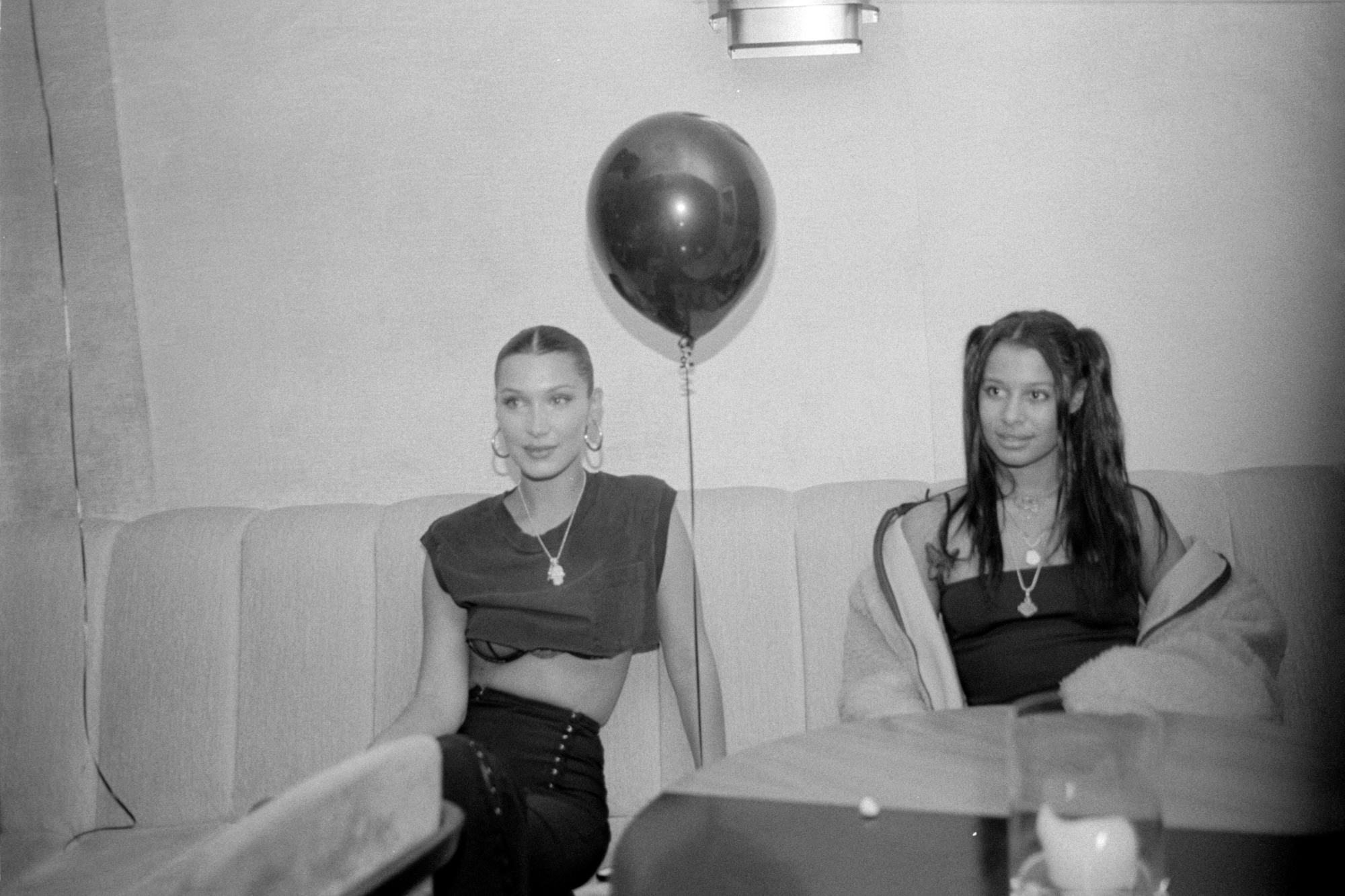 Bella Hadid and Sami Miro sitting in a booth.