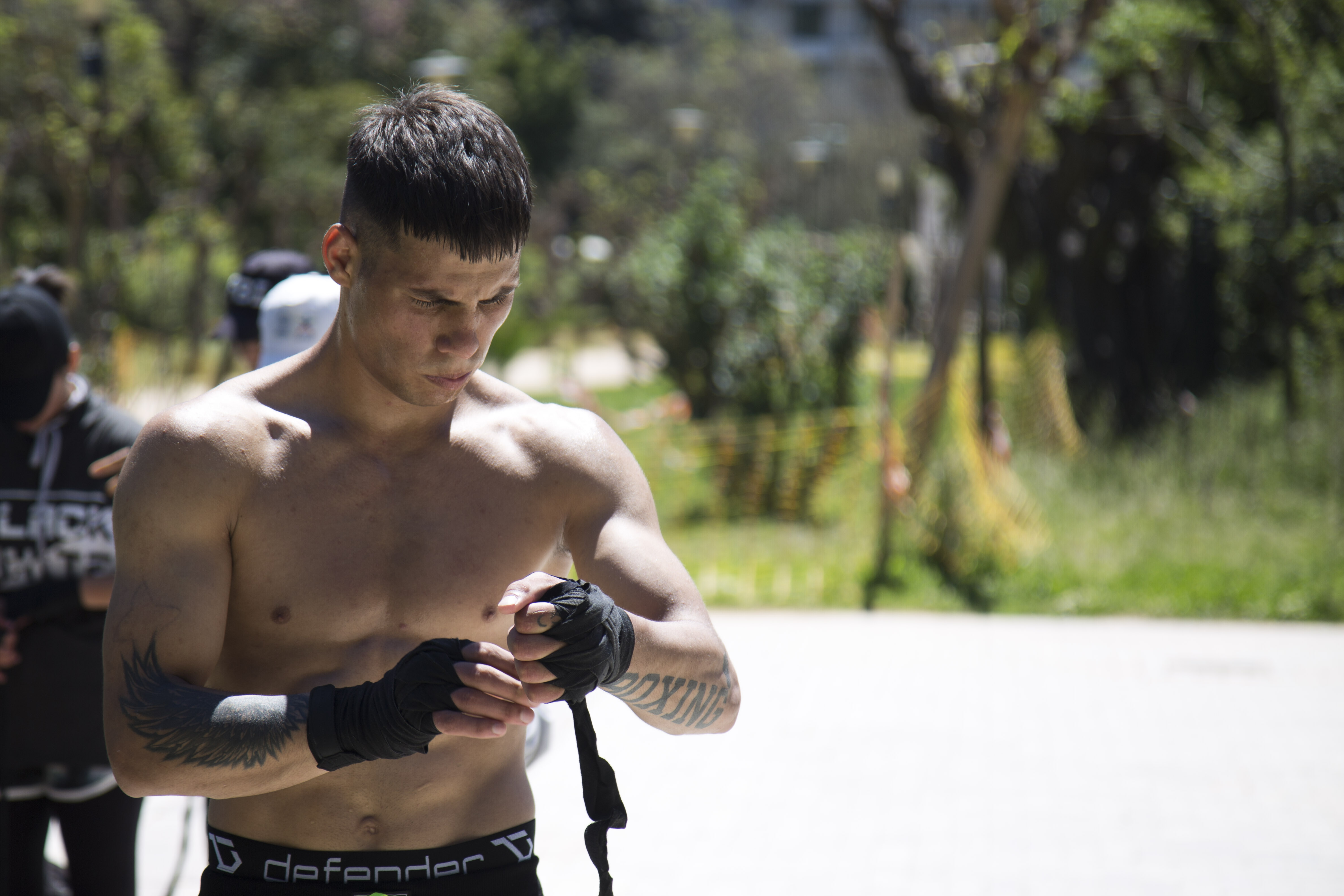 IQBAL ALIKHIL - Muscular man with short hair and straight bangs putting on gloves.