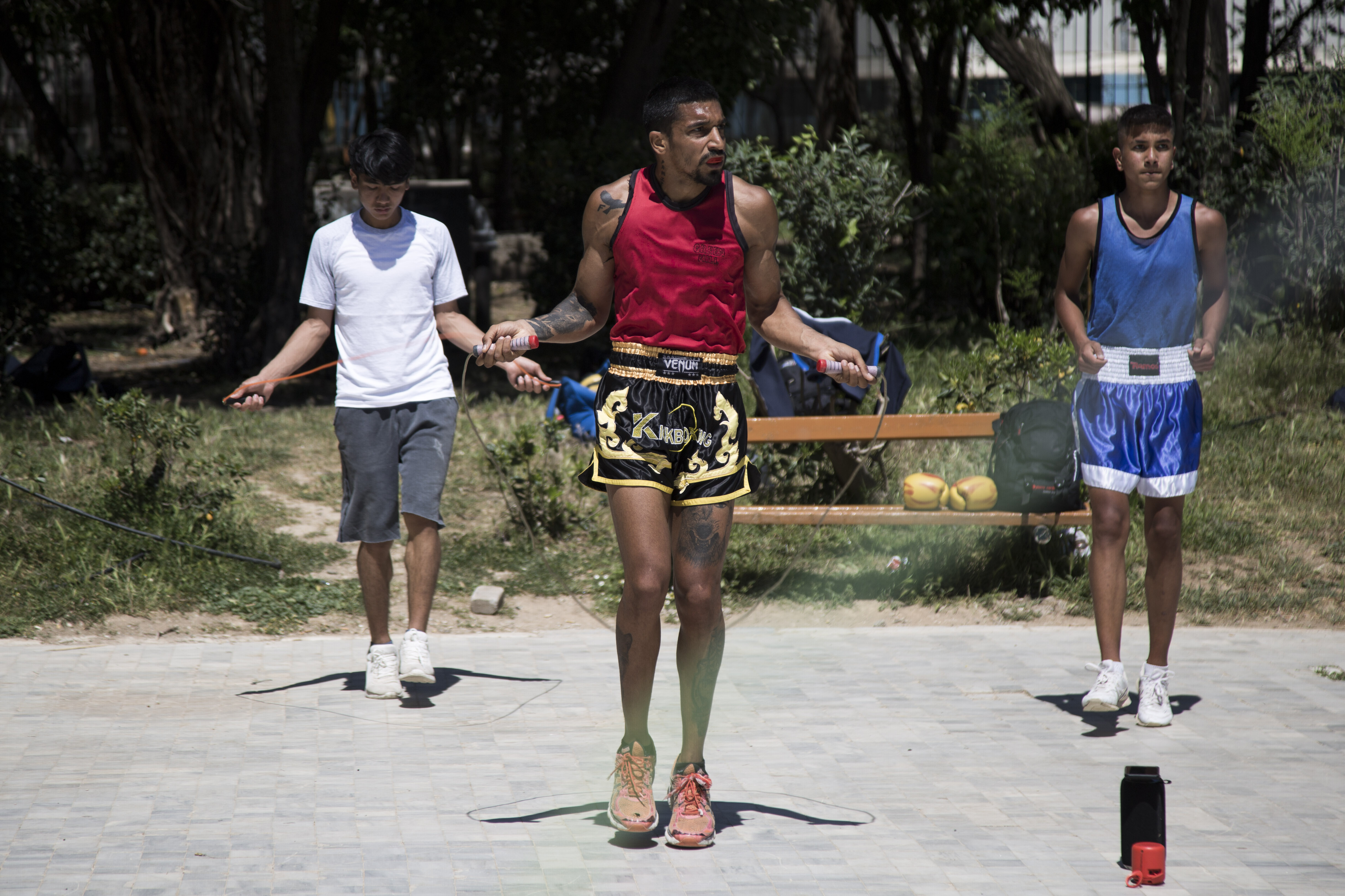 HAMID NOROUZI - A man and two teens skipping rope in the park.