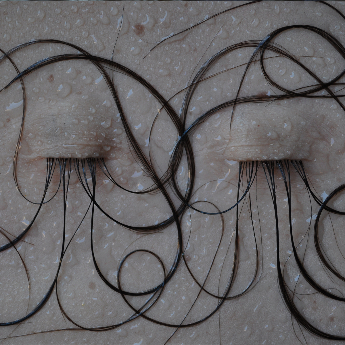 Scultura di carne sintetica bagnata, capelli e occhi chiusi.