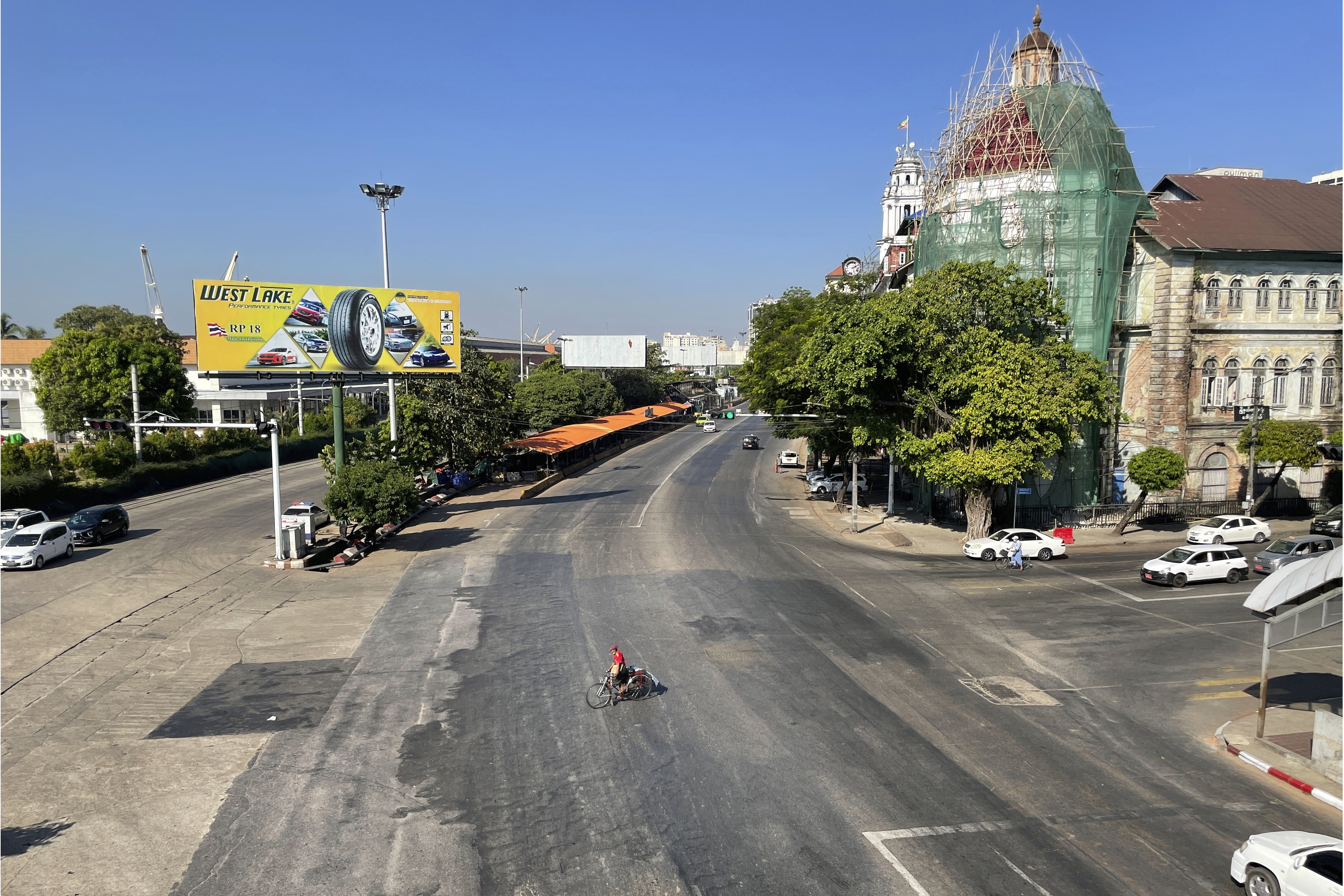 A single cyclist crosses an empty Yangon street. Photo: AP/STR