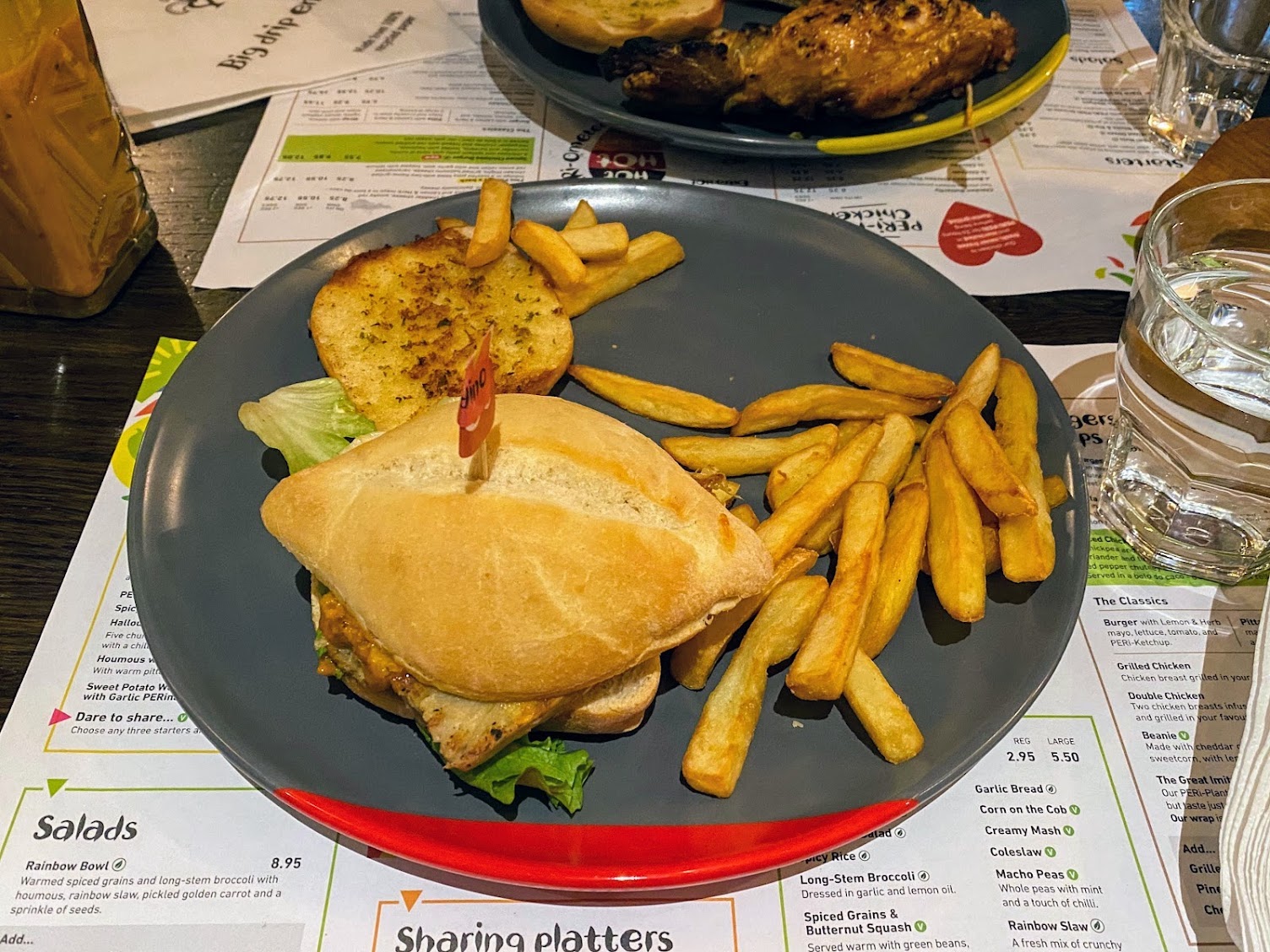 Nando's Great Imitator Burger on a plate with peri peri chips and garlic bread