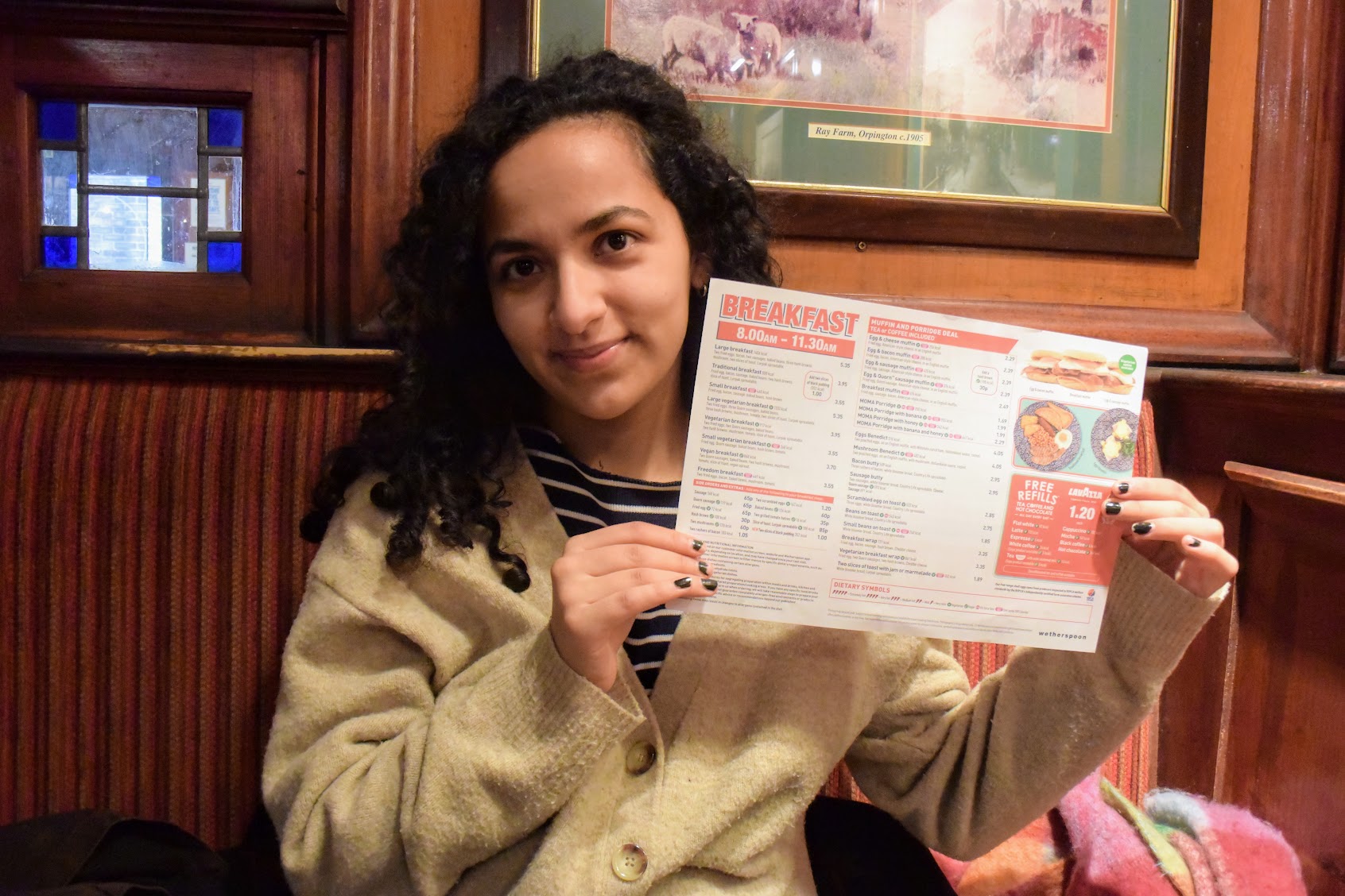 Carla Abreu holding up the Wetherspoons menu in a pub