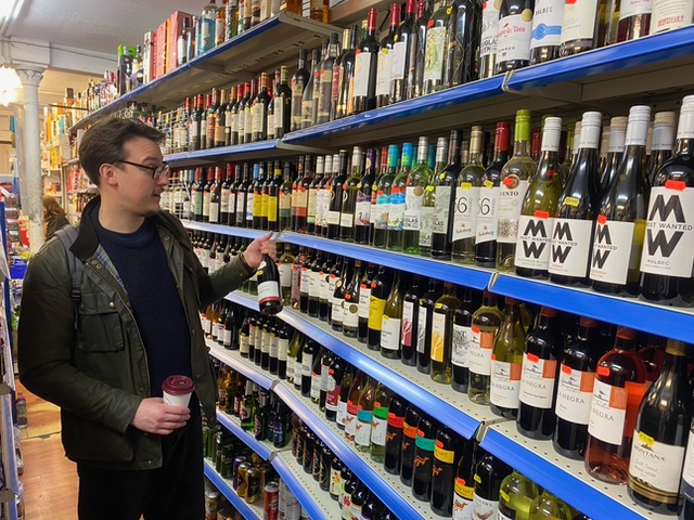 Bert Blaize selecting wine at City General Store, a London corner shop.