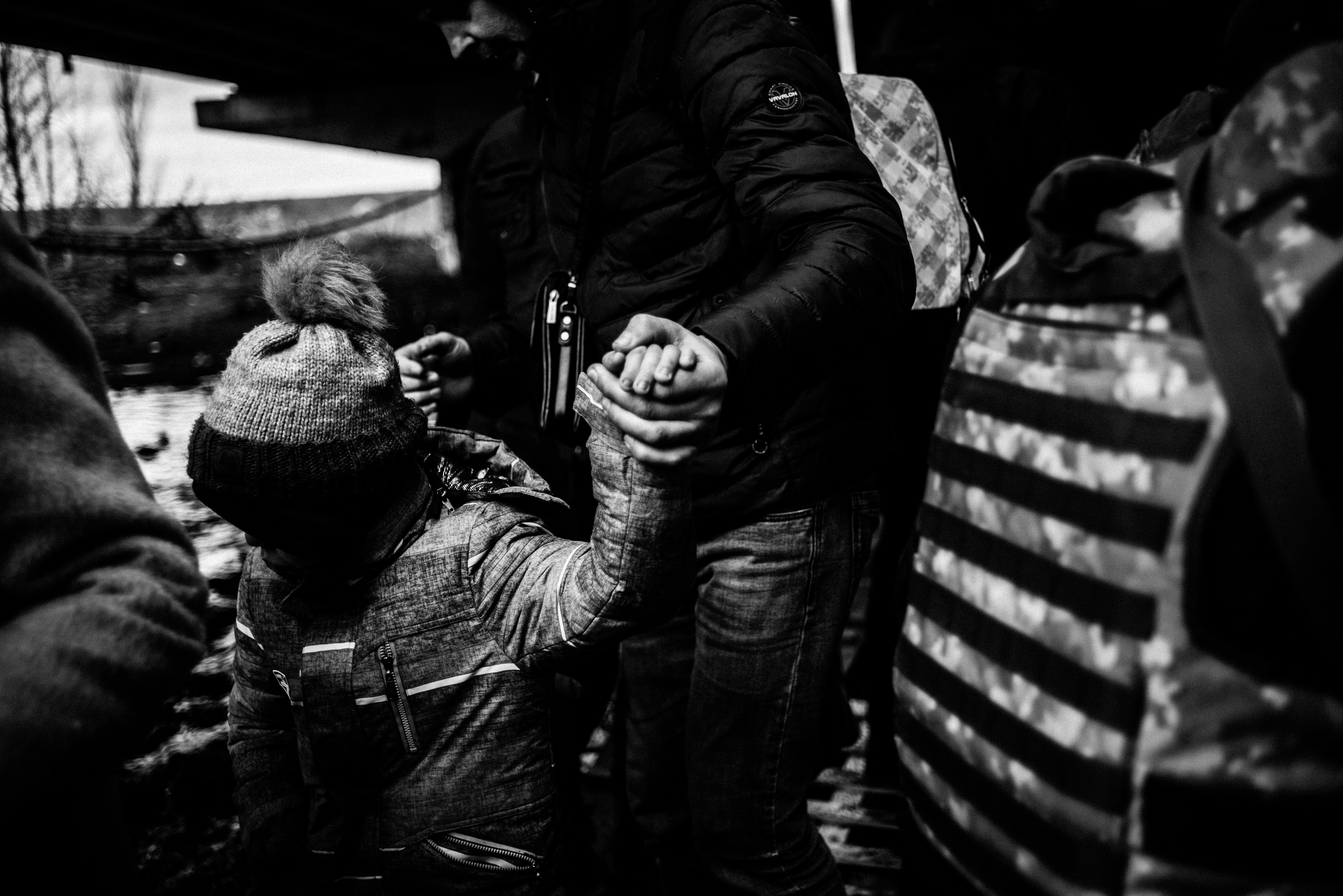 A father holds his son's hand as they try to leave the violence behind them.