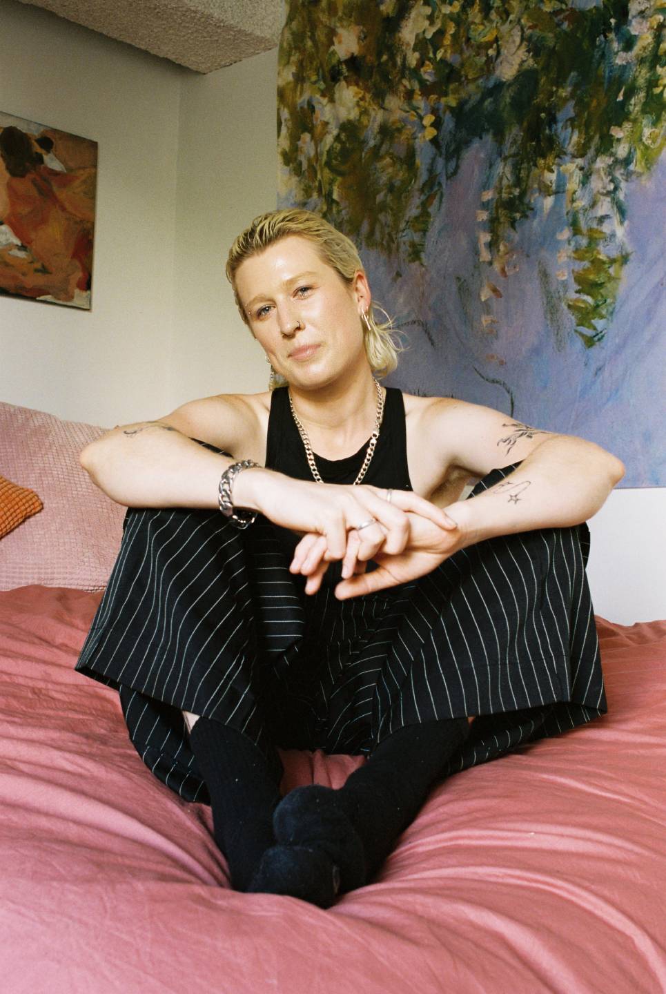 Nonbinary person with short hair sat on bed