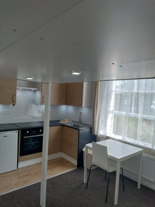 Tiny kitchenette in a one-bed bedsit in Crouch End with the staircase cut into a wardrobe
