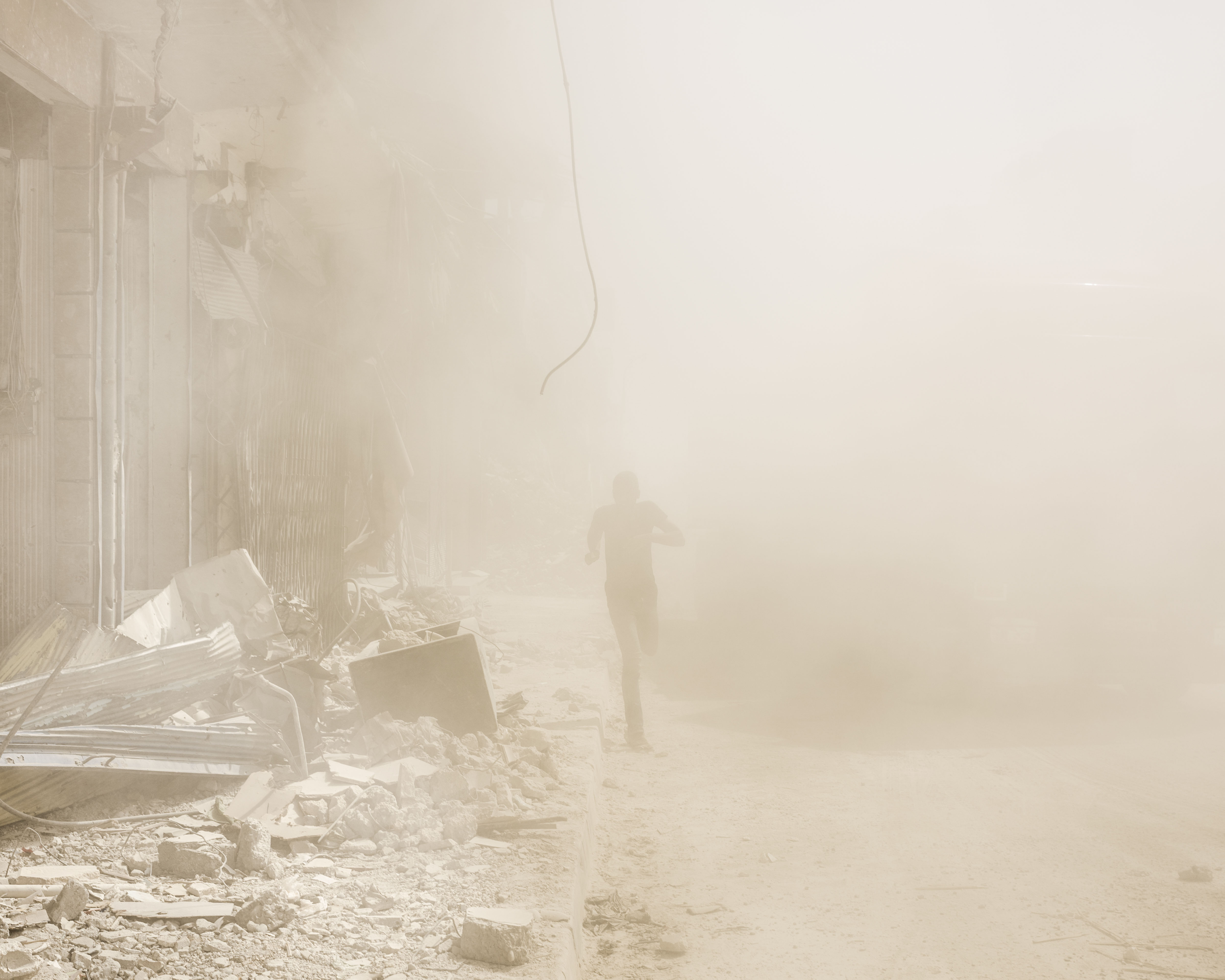 A man runs from a falling building in Raqqa. After the Islamic State was defeated here, civilians started to slowly return although much of the city still lies in ruins.